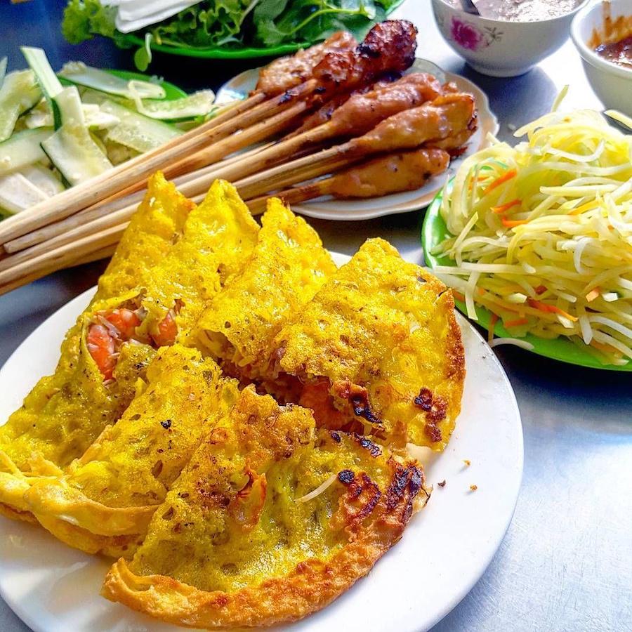 Crispy Banh Xeo pancakes served with herbs, pickles and grilled skewers