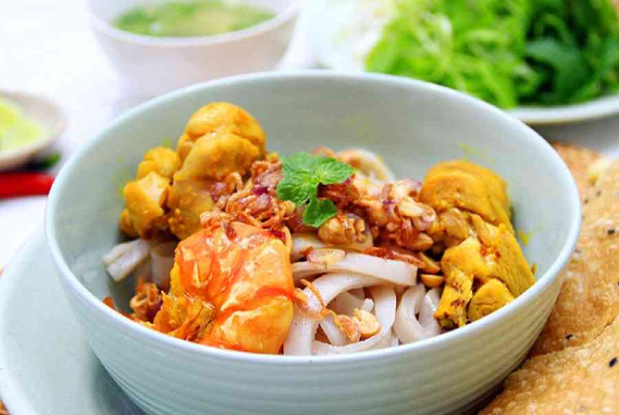 A bowl of Mi Quang with noodles, shrimp, meat, herbs and rice cracker